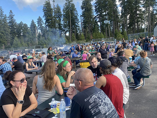 School families sitting at tables enjoying BBQ