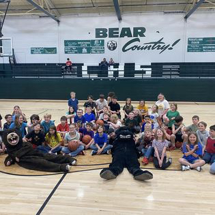 Group of little league basketball students on gym floor with mascots