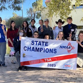 Group of students outside holding up State Champions banner