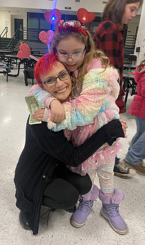 Woman hugging student at the Valentine Dance 