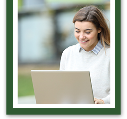 Young lady smiling while working on her laptop outside